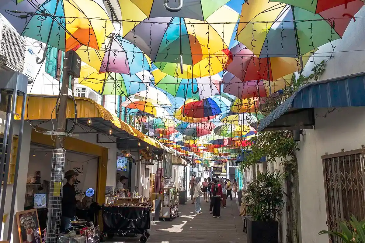 Colourful umbrella-covered street in George Town, Penang, with pedestrians and small shops