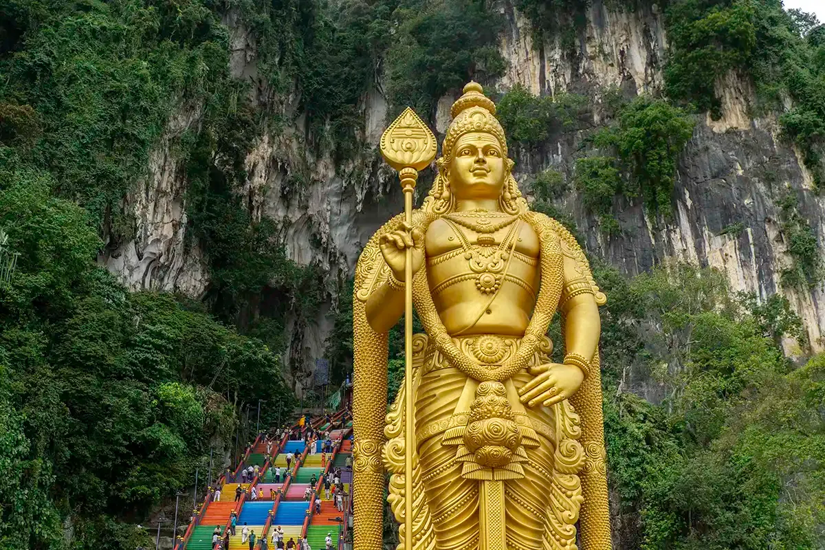 Golden Lord Murugan statue and rainbow steps at Batu Caves, an optional sightseeing stopover on the Kuala Lumpur to Taman Negara private transfer.