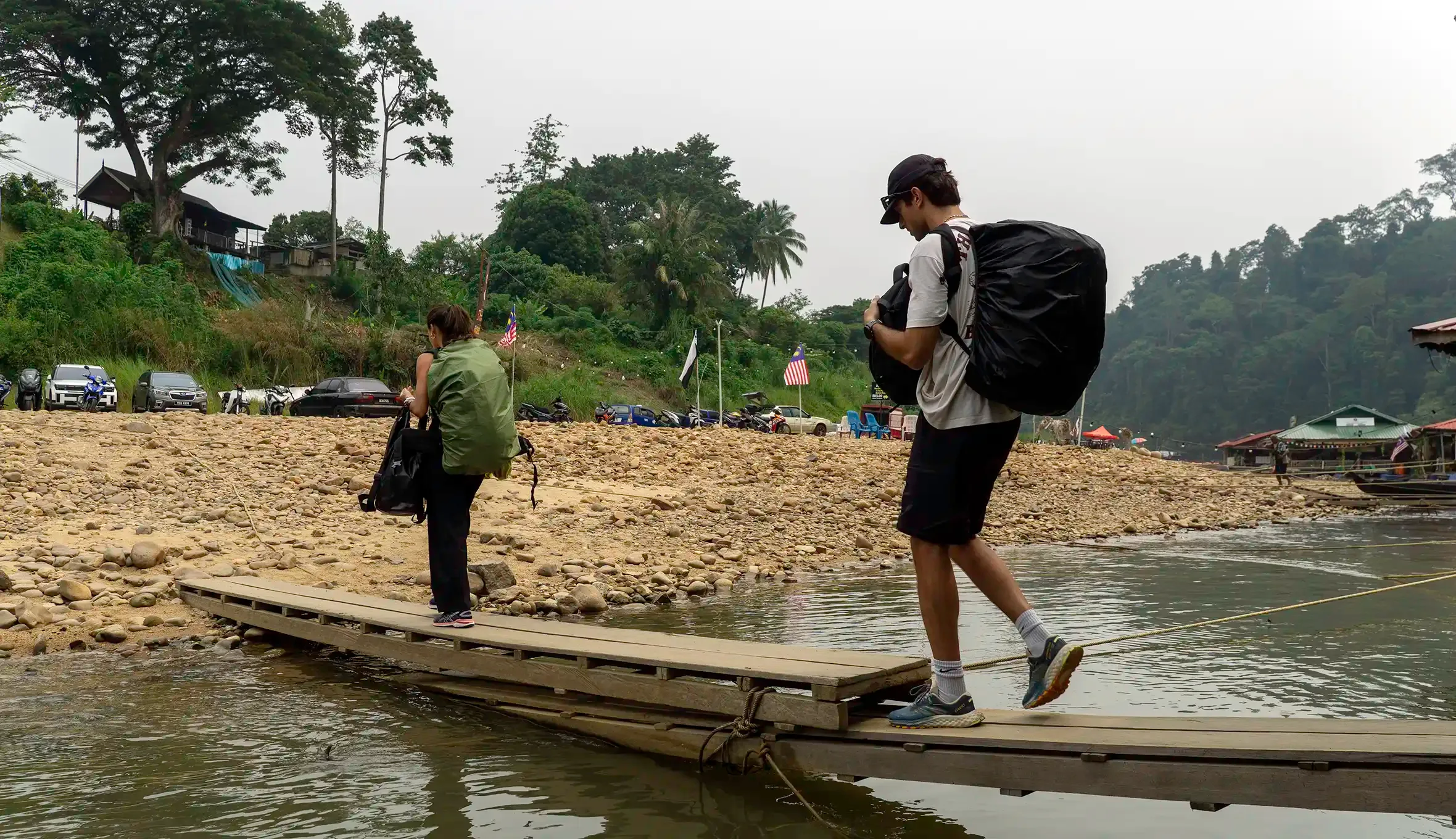 Travellers carrying luggage across the jetty walkway after arriving at Kuala Tahan, Taman Negara