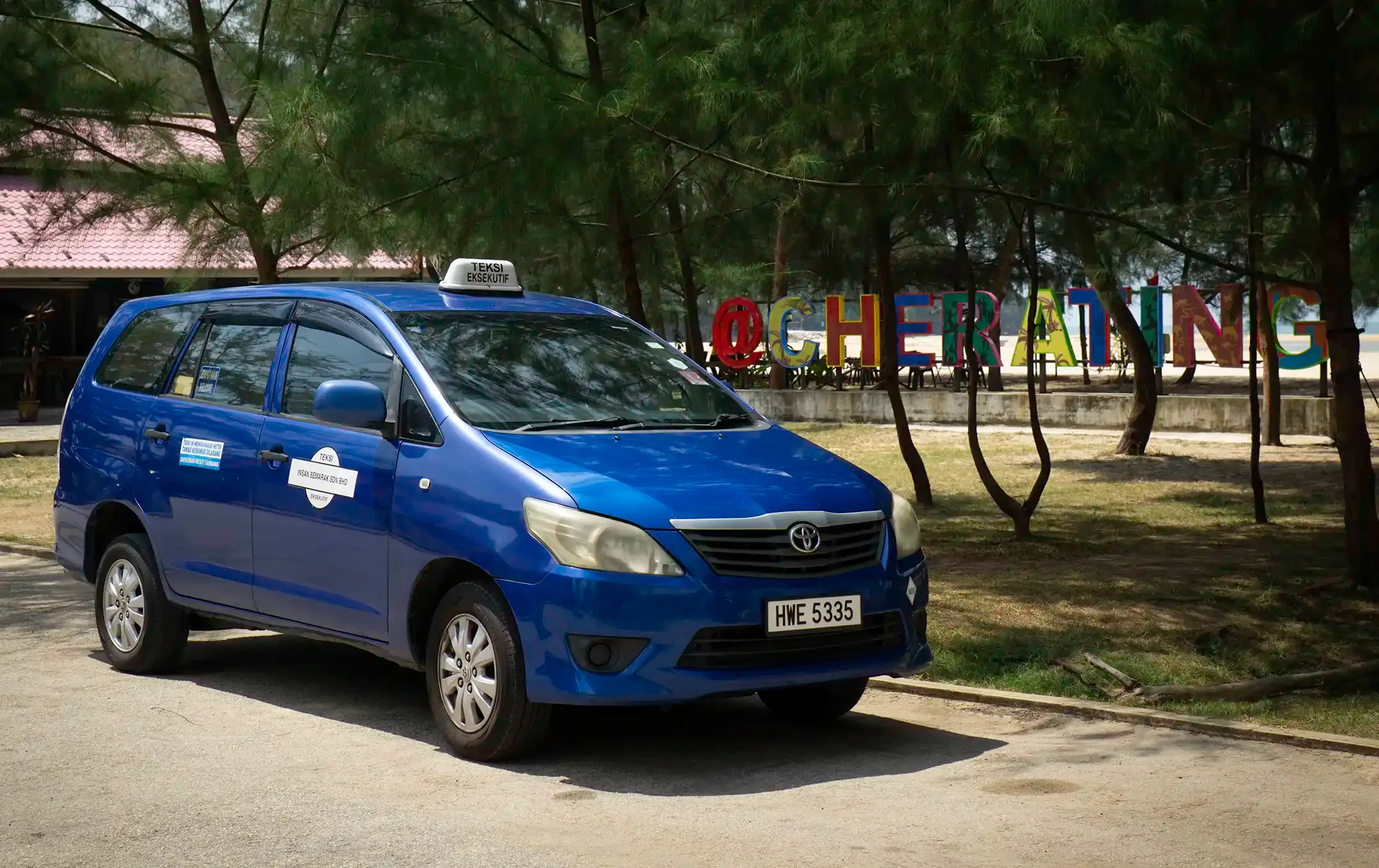 Blue Toyota Innova taxi parked near the Cherating beach sign in Pahang