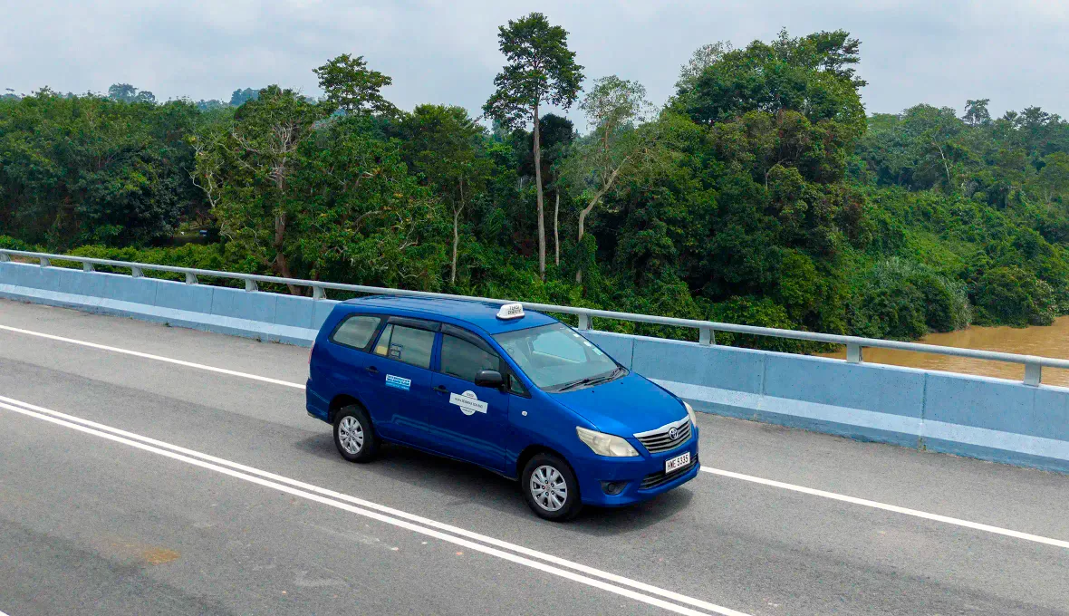 Private transfer vehicle crossing the road bridge from Kuala Tembeling to Kuala Tahan, Taman Negara, carrying tourist luggage by road.